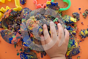 Hand of child playing multicolored kinetic sand. children activity game toy for model forming craft and sculpture art