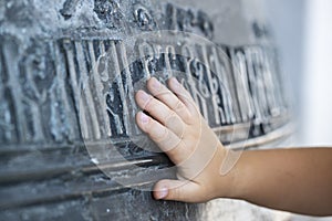 The hand of the child touches a large church bell with ancient Slavic inscriptions. The concept of spirituality. Russia. Rostov th