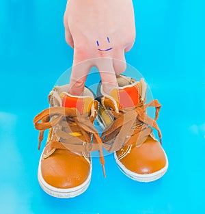 Baby shoes on a blue background with a hand