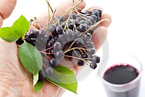 Hand with chokberries, glass with aronia juice