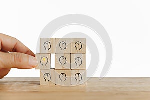 Hand choose bright light bulb in human`s head icon on wooden cube  for creative idea and innovation , outstanding,