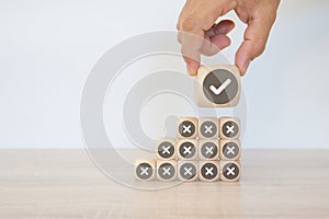 Hand choose check mark with cross symbol on cube wooden block stack for true or false changing mindset or way of adapting to