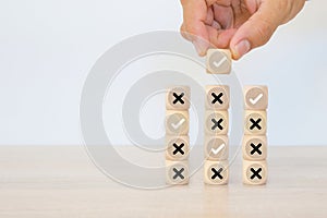 Hand choose check mark with cross symbol on cube wooden block stack for true or false changing mindset or way of adapting to