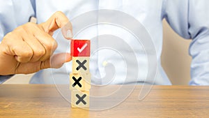 Hand choose check mark on cube wooden toy block with cross symbol for true or false changing mindset or way of adapting to change