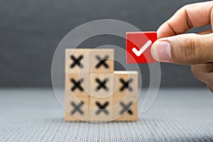 Hand choose check mark on cube wooden toy block with cross symbol for true or false changing mindset or way of adapting to change