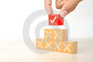 Hand choose check mark on cube wooden toy block with cross symbol for true or false changing mindset or way of adapting to change