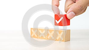 Hand choose check mark on cube wooden toy block with cross symbol for true or false changing mindset or way of adapting to change