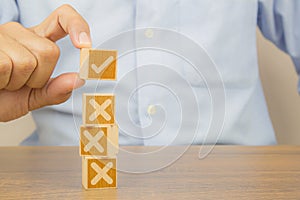 Hand choose check mark on cube wooden toy block with cross symbol for true or false changing mindset or way of adapting to change