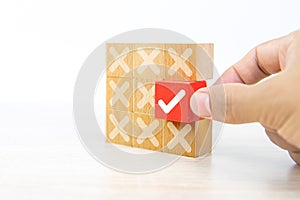 Hand choose check mark on cube wooden toy block with cross symbol for true or false changing mindset or way of adapting to change