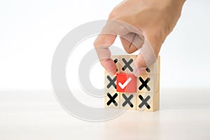 Hand choose check mark on cube wooden toy block with cross symbol for true or false changing mindset or way of adapting to change