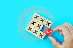 Hand choose check mark on cube wooden toy block stack with cross symbol for true or false changing mindset or way of adapting to