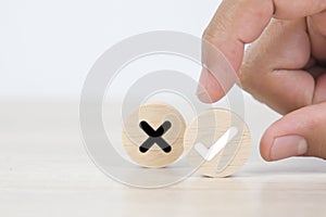 Hand choose check mark on wooden toy with cross symbol for true or false changing mindset or way of adapting to change