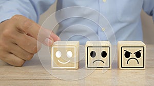 Hand choose smile face on wooden block stack for customer services rating feedback satisfaction survey review questionnaire