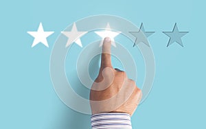 Hand choosing 3 stars rating on blue background - Average feedback concept