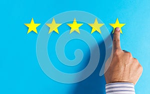 Hand choosing 5 stars rating on blue background