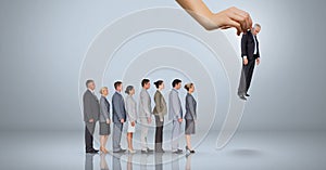 Hand choosing a business man on grey background with business people