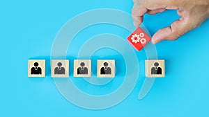 Hand choosing cog icon with people symbol on cube wooden toy block stacked. Concepts human resources personnel selection person