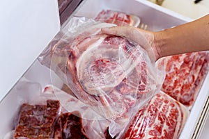 Hand choosing fresh raw ribs meat in freezer