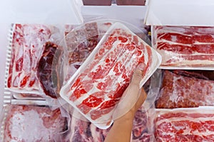Hand choosing fresh raw yakiniku meat in freezer