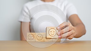 Hand choosing happy face from Emotion block for customer review, good experience, positive feedback, satisfaction, survey,