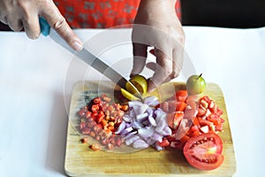 Hand chopping an orange on a plate full of vegetables