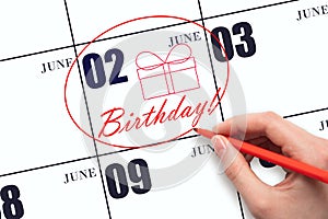 The hand circles the date on the calendar 2 June, draws a gift box and writes the text Birthday. Holiday.