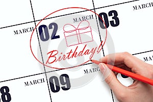 The hand circles the date on the calendar 2 March, draws a gift box and writes the text Birthday. Holiday.