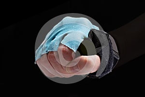 Hand clasped fist in black glove with blue with open fingers isolated on black background