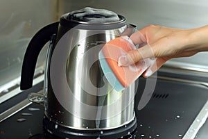 hand cleaning electric kettle with a nonabrasive sponge and soap