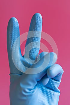 Hand with cleaning glove making fist. Hand in a rubber glove on a pink background. vertical photo