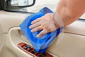 Hand cleaning interior car door panel with microfiber cloth