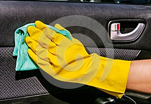 Hand cleaning interior car door panel with the microfiber cloth . Worker at the car wash.