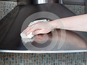 Hand cleans stainless kitchen hood closeup