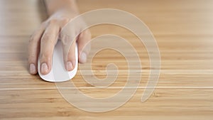 Hand Clicking on white computer mouse on the wooden desk photo