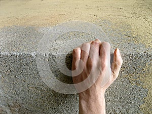 Hand clinging to a concrete block, concept of risk or strength