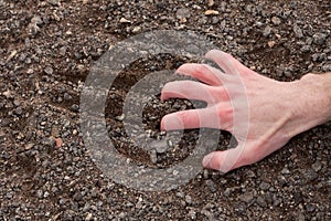 Hand clinging to a stony ground photo