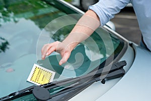 Hand close up holding a parking ticket placed on car windscreen