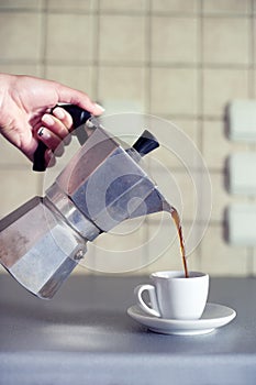 Hand close up pouring espresso coffee in a cup