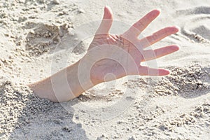 Hand closeup. Hands buried in sand on a beach.