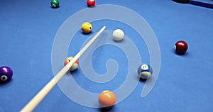 Hand and club on billiard table with moving white ball