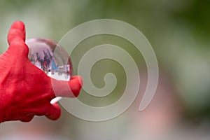 Hand clutching glass sphere with people apparently captured inside