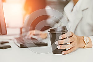 Hand at coffee cup in office desk. business people drinking coffee from paper cup for good work concept