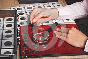 Hand with coin, box with collectible coins in the cells and a page with coins in the pockets