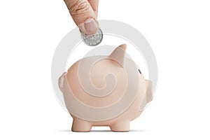 Hand with coin over a piggy bank on white background. concept of preserving and saving money