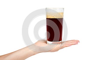 Hand with cold glass of dark beer or kvass with foam isolated on white background.