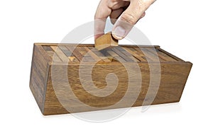 Hand is collecting pieces of wooden bricks in the box after playing Jenga game,Blocks wood Jenga game on white background