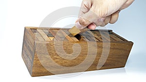 Hand is collecting pieces of wooden bricks in the box after playing Jenga game,Blocks wood Jenga game on white background