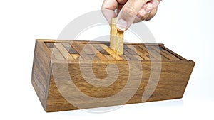 Hand is collecting pieces of wooden bricks in the box after playing Jenga game,Blocks wood Jenga game on white background