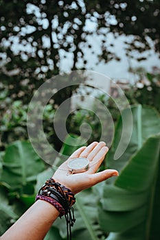 Hand with compass in the lush rainforest jungle