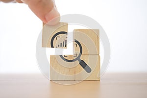 Hand complete magnifying glass with crop and increasing graph inside icon on wood block for business growth, focus on target